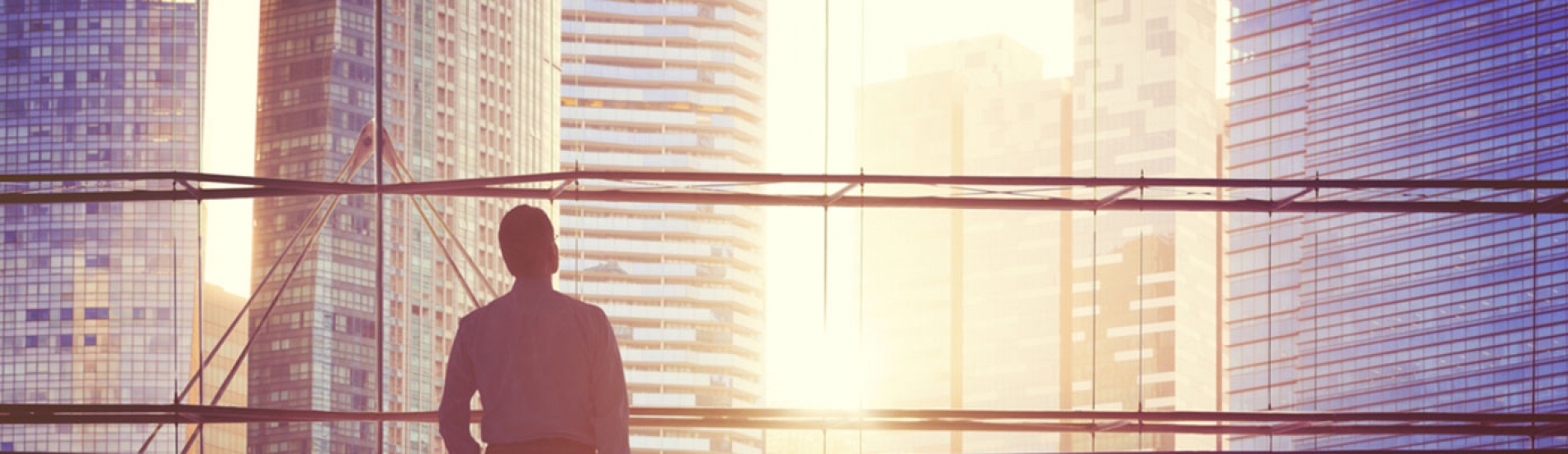 man looking at buildings from office window